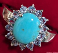 Close-up of the silver ring featuring a central turquoise cabochon stone with surrounding tanzanite stones, showing the front side and stone details.