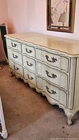 Full view of the antique white dresser showing nine drawers and curved front design. Painted white with distressed finish.
