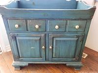 Front view of blue antiqued French Provencal cupboard showing two drawers with white knobs and two cabinet doors below.