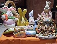 Overview of various Easter-themed bunny figurines and decorative eggs arranged on an orange surface