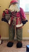 Full view of the life-size Santa figure standing against a wall