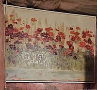 Full view of framed canvas painting of poppies showing red and orange flowers with green foliage on a light background, metal frame visible.