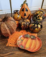 Wide view of all decorative pumpkins, placemats, and pumpkin platter arranged on wooden floor.
