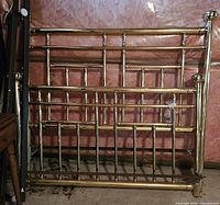 Full view showing queen brass headboard, footboard, and frame parts leaning against wall.
