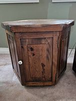 Front side view showing cupboard door with a white knob, wood grain and knots visible.