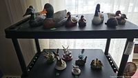 Top shelf displays wood bird decoys, including several wood ducks and one wood beaver with some damage visible on a wood duck.
