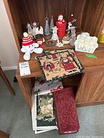 Overview of Christmas figurines, ornaments and folded fabric placemats on wooden furniture