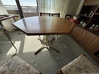 Wide-angle photo of the octagonal wood dining table in a room showing the metal pedestal base and overall table shape.