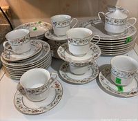 Overall view of the floral patterned cups, saucers, stacked plates, and cream and sugar containers showing the collection and pattern.