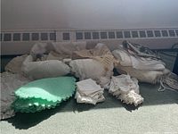 Photo showing assorted textiles including crocheted and knitted doilies laid out on carpeted floor, with a green doily prominent
