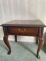 Front view of wooden end table showing drawer and Queen Anne style legs.