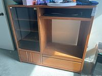 Full front view of MDF entertainment stand showing left glass door with shelves, central TV space, and bottom drawers and doors