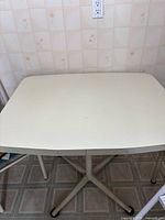 Top view of cream-colored vintage kitchen table with rounded edges.