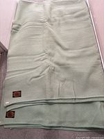 Two folded green Westfield all wool blankets stacked with black and gold labels showing ram's head logo and brand name.