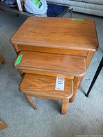 Three wooden nesting tables stacked together showing size progression and wood grain finish.