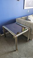 Side table showing reflective mirrored glass top, metal tubular frame, and leg design from corner perspective.