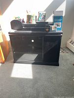 The entire lot placed on and around the black MDF TV stand in a sunny room.