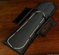 Full view of the necklace inside the black fabric-lined case showing the arrangement of pearls and amethyst beads.