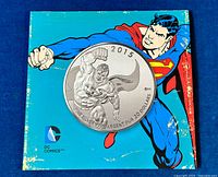Front cover of the collector's folder featuring an illustration of Superman flying and overlay image of the commemorative silver coin.