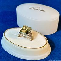 Close-up front angled view of the 925 sterling silver ring featuring a large rectangular yellow stone, placed on a white cushioned ring holder with a 'Favorite Jewel' lidded container behind it.