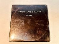 Front cover of Emerson Lake & Palmer Works Volume 1 album, showing black background with white text and logo. Visible signs of wear and ring marks on sleeve.