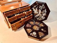 Wooden jewelry chest with open drawers alongside octagonal black lacquer box with lid propped