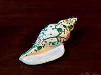 Sea snail porcelain figurine, top/side view showing floral vine pattern and glossy finish.