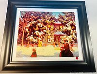 Framed print showing city street winter scene with snow, figures, and framed in wide grey frame under glass.