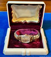 Watch displayed in vintage cream and burgundy velvet watch box showing the full set.