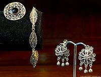 Photo showing the bracelet, brooch, and a pair of filigree dangle earrings together on display.