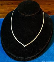 Front view of the sterling silver herringbone necklace displayed on black velvet stand showing the V-shape dip at clavicle area.