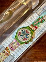 Swatch chronograph watch with elaborate Russian Treasury design in plastic clear case on Swatch branded background.