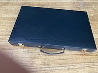 Closed black backgammon case on wood surface