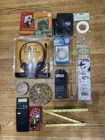 Full view of box contents showing various electronics, tools, tapes, and accessories on wooden surface.