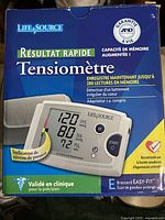 Front side of the LifeSource blood pressure monitor box showing the device display with pressure readings 120/80 and pulse 72, French text indicating quick results, 280 readings memory, irregular heartbeat detection, and included AC adapter.