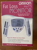 Photo of original Omron Fat Loss Monitor packaging box showing product name and device image