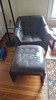 Front view of dark brown leather armchair and ottoman on hardwood floor