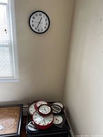 Widow wall clock and nine other clocks resting on furniture showcasing different sizes and frames.