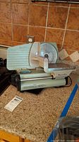 Image showing the full deli slicer machine with body, circular blade, sliding carriage, and handle on a countertop.