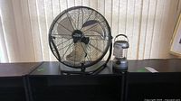 The Comfort Zone high velocity floor fan and unmarked lantern placed side by side on a surface.