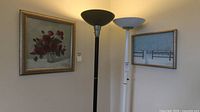 Photo showing both framed paintings on the wall with two floor lamps beneath.