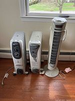 View of two Pelonis space heaters and one Aloha Breeze tower fan side by side on floor near window