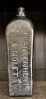 Photo of black glass antique bottle with embossed lettering showing brand 'Blankenheym & Nolet'