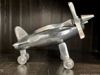 Side profile of a heavy metal vintage airplane figure with propeller and wheels on a shelf.