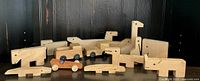 Photo showing nine handmade vintage wooden toys in natural wood finish including animal and vehicle shapes such as a long-necked dinosaur and train cars.