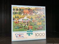 Photo of the boxed 1000 piece jigsaw puzzle by Charles Wysocki titled 'Rally at Dandelion Mill' showing the puzzle artwork and branding on the box front.