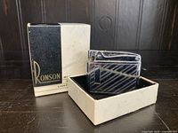 Ronson table top lighter with diagonal stripes next to original branded box on dark surface