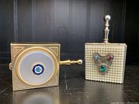 Two vintage miniature ladies purse ashtrays placed side by side on dark background, one with faux pearl texture and decorative gemstones, the other gold-tone with handle
