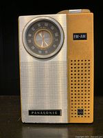 Front view of vintage Panasonic transistor radio with FM-AM dial, speaker grille, and yellow casing