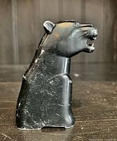 Side view of the vintage black panther table top lighter showing its form and surface wear.